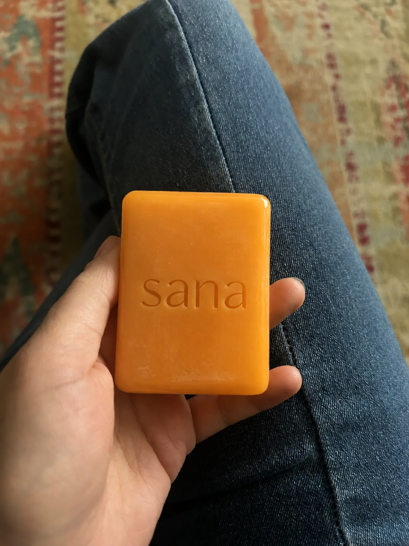 The vibrant persimmon-orange sana bar, held in hand